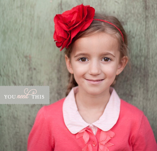 Smiling girl with red rose headband and pink cardigan