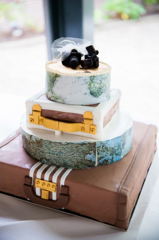 Wedding cake with suitcase tiers and travel-themed decor on top