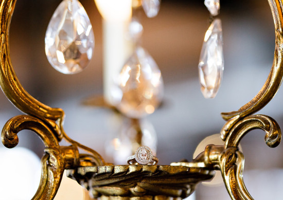 Diamond ring on ornate gold chandelier with crystals