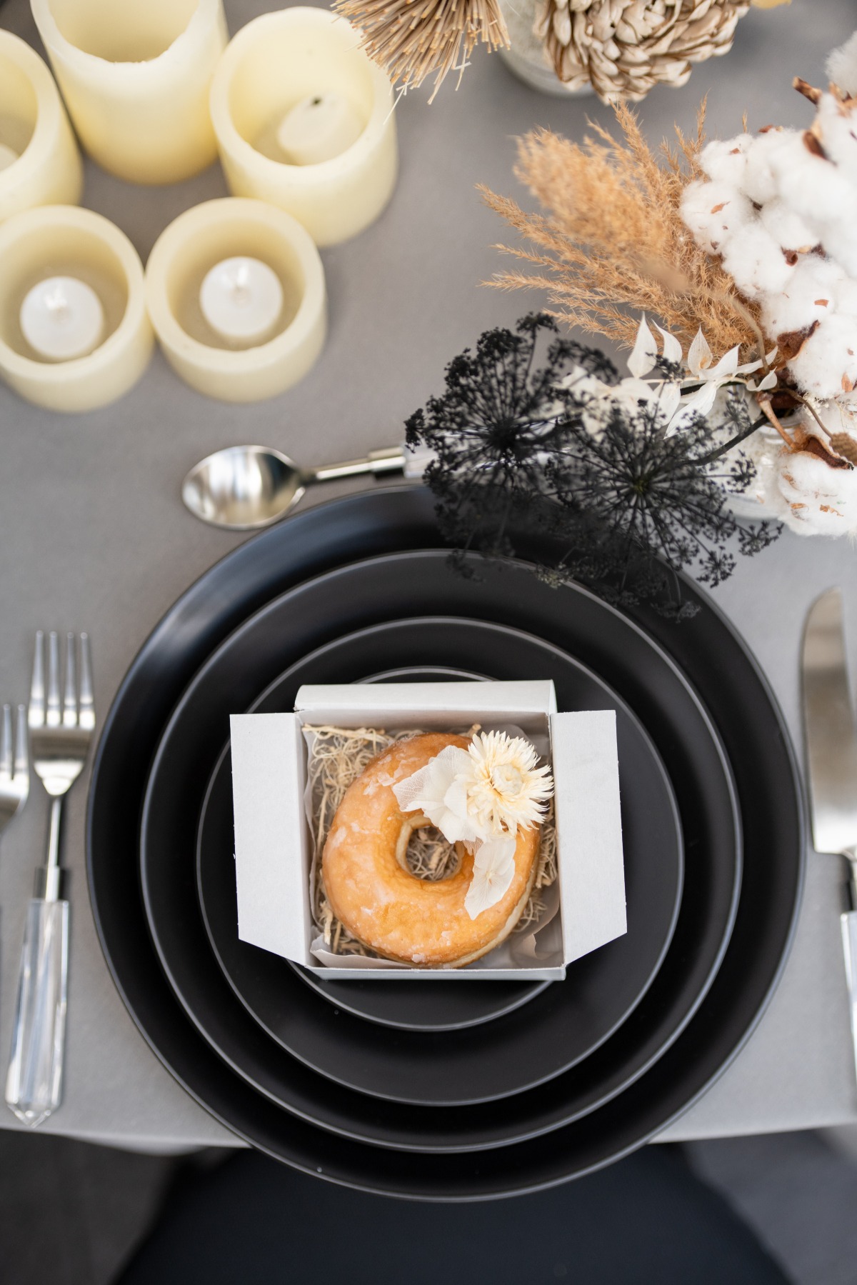 Elegant table setting with a glazed donut on black plates