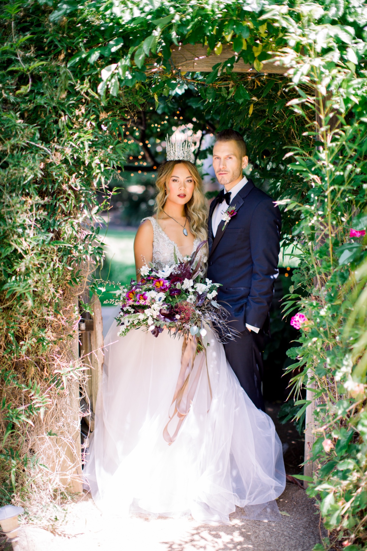 Bride and groom portrait under green garden archway