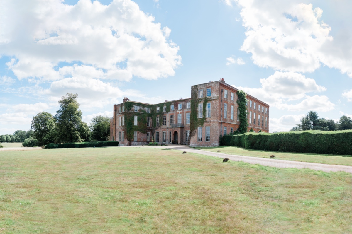 Elegant country house in a field with ivy on walls, bright day