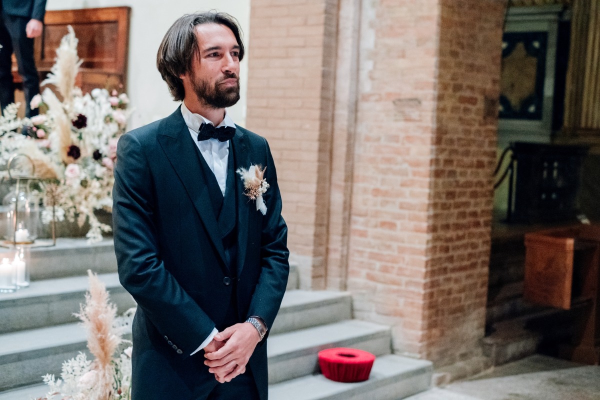 Groom in elegant black suit awaits wedding ceremony