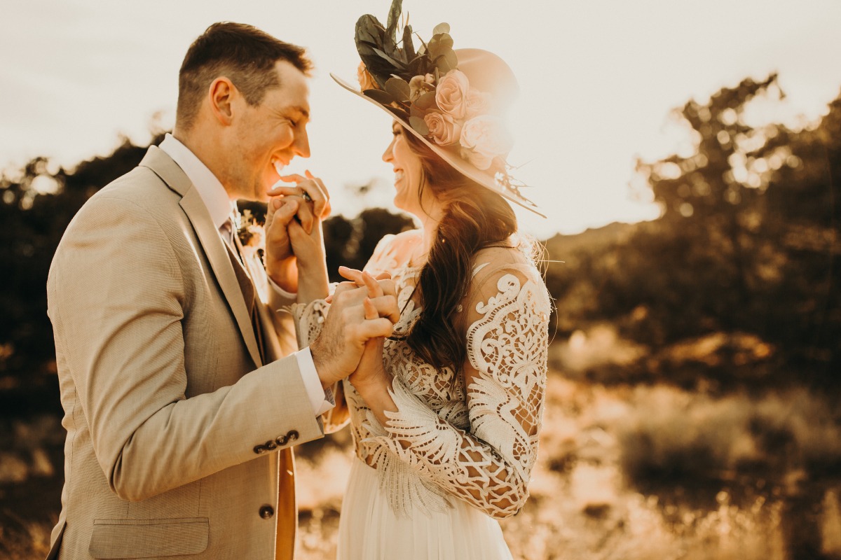 Happy couple holding hands at sunset wedding