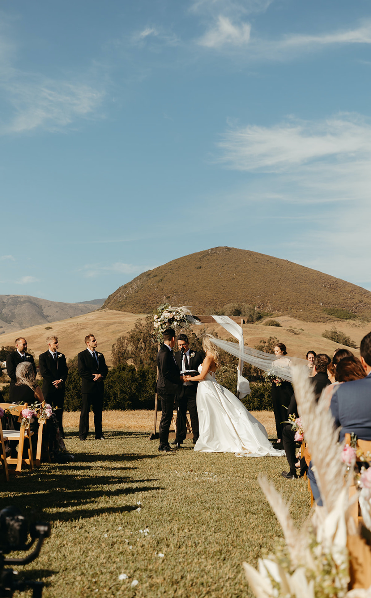 Scenic outdoor wedding ceremony with bride groom and guests